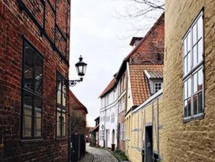 Seitengasse mit gepflasterter Straße und historischen Wohnhäusern mit roten und gelben Fassaden in Lünen – charakteristisches Stadtbild