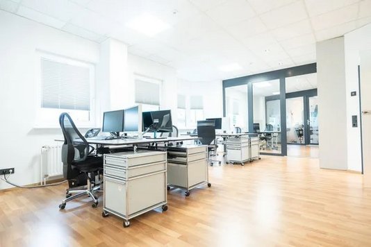 Büroarbeitsplätze mit Computern und Stühlen im Verwaltungsbereich der Ergo Versicherung – Kooperationspartner im Bereich Hausbau-Versicherungen.