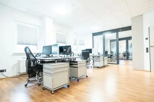 Büroarbeitsplätze mit Computern und Stühlen im Verwaltungsbereich der Ergo Versicherung – Kooperationspartner im Bereich Hausbau-Versicherungen.