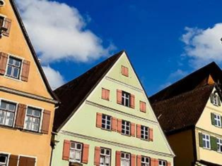 Drei Altstadthäuser aus der Froschperspektive in Werne mit farbigen Fassaden – orange, grün und hellgelb – und braunen Holzfensterbänken