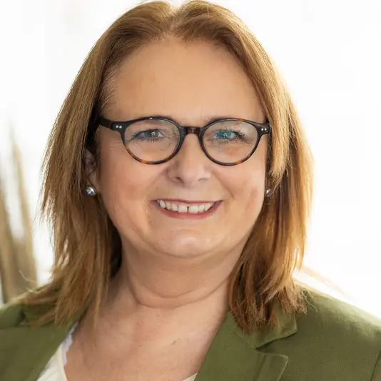 Freundlich lächelnde Hauskaufberaterin mit Brille – Ansprechpartnerin für Immobilien und Baufinanzierung