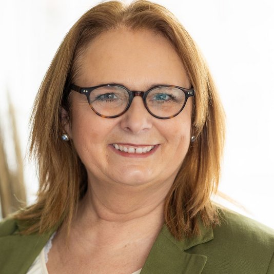 Freundlich lächelnde Hauskaufberaterin mit Brille – Ansprechpartnerin für Immobilien und Baufinanzierung