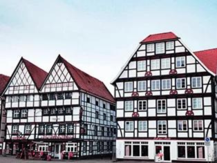 Zwei Fachwerkhäuser mit roten Dächern in der Innenstadt von Unna – traditionelle Architektur mit Geschäftseingang und Blumenschmuck