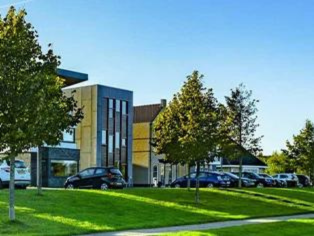 Grünfläche mit Spazierweg, Bäumen und moderner Wohnbebauung im Hintergrund in Schwerte – Beispiel für stadtnahe Baugebiete